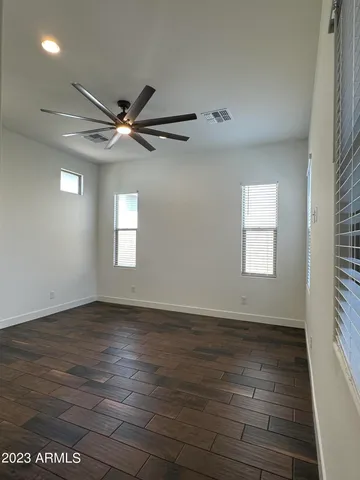an empty room with wooden floor fan and windows