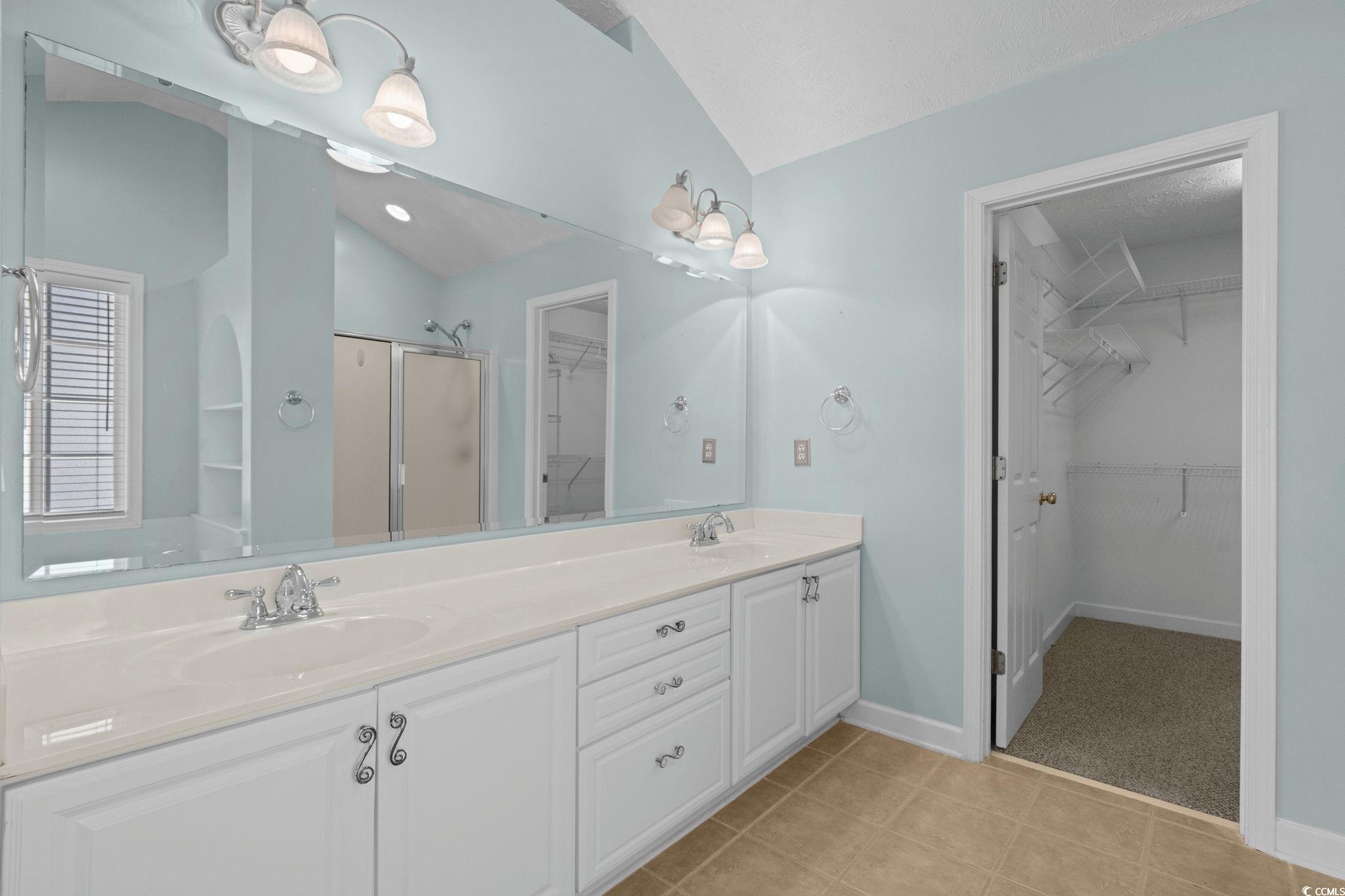 613 Broad River Road Myrtle Beach, SC 29588 - Photo 24 of 40 Bathroom with a walk in closet, a shower stall, double vanity, vaulted ceiling, and light tile patterned floors