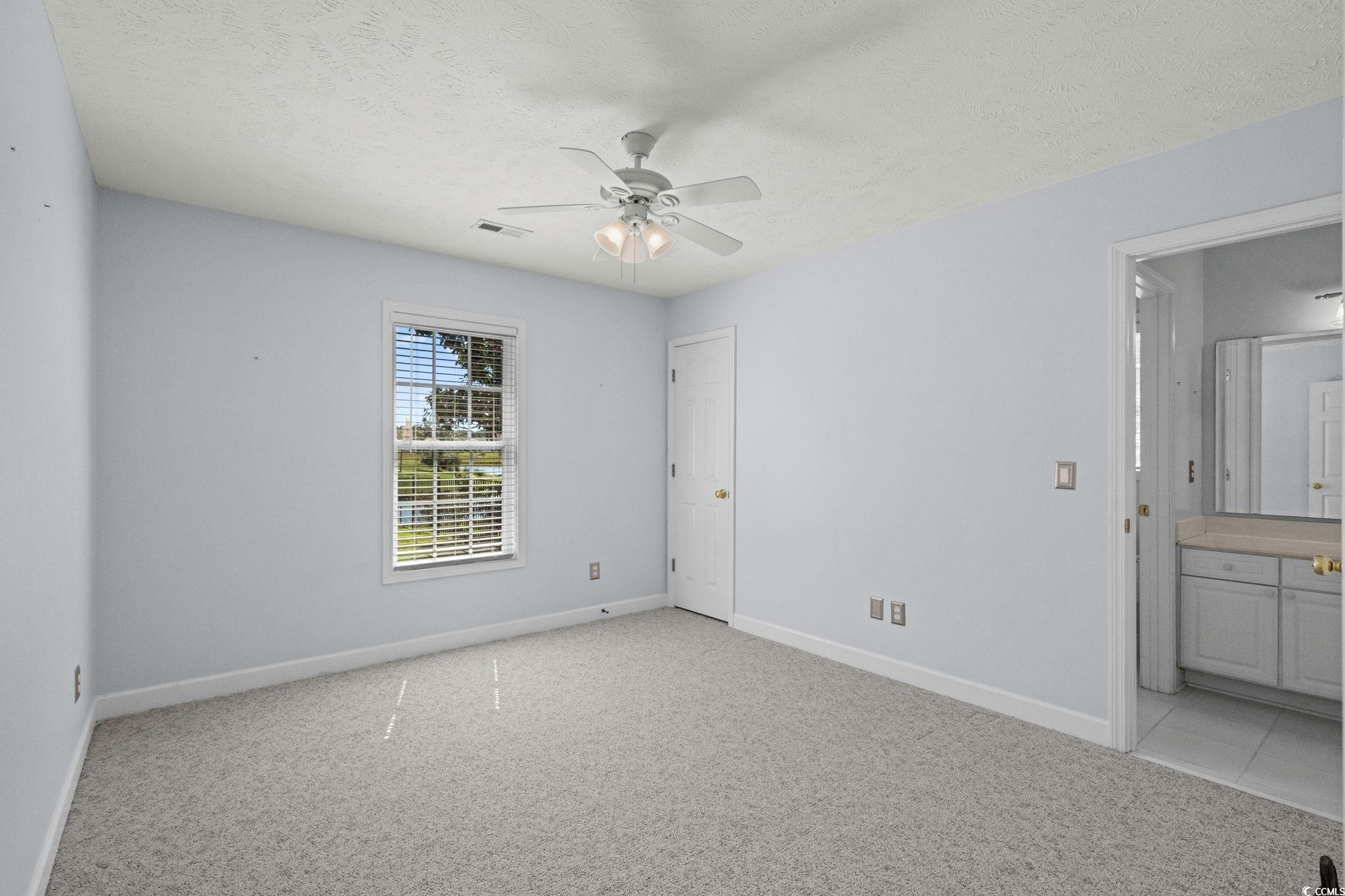 613 Broad River Road Myrtle Beach, SC 29588 - Photo 27 of 40 Unfurnished bedroom with a textured ceiling, light colored carpet, ceiling fan, and connected bathroom