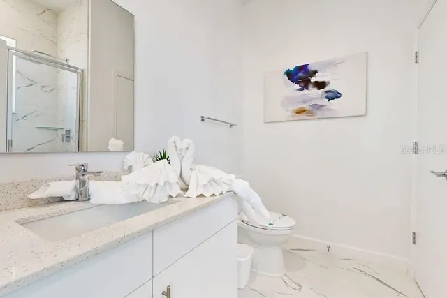 a bathroom with a granite countertop sink and a toilet