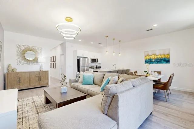 a living room with furniture kitchen view and a wooden floor