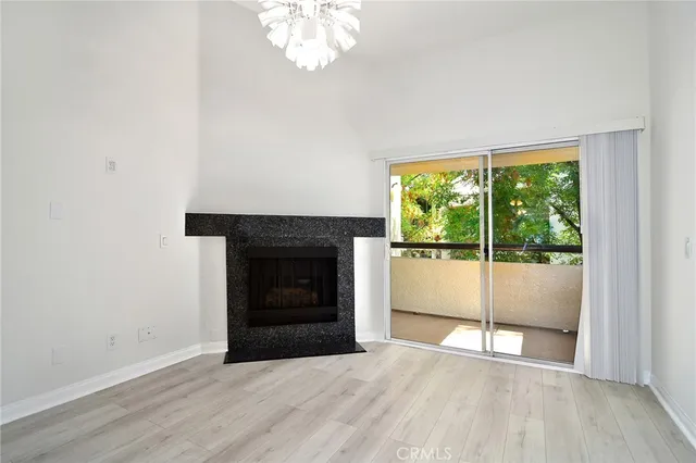 an empty room with wooden floor fireplace and windows