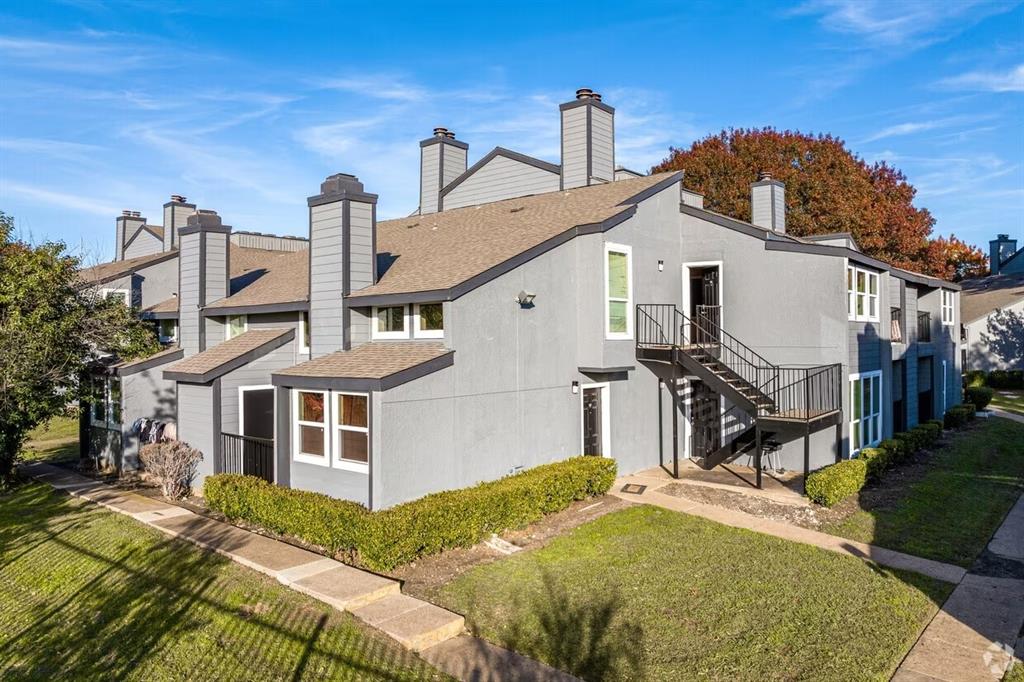9696 Walnut Street, Unit 1216 Dallas, TX 75243 - Photo 2 of 16 Exterior view of the property featuring a gray facade, multiple windows, and exterior stairs with black railings