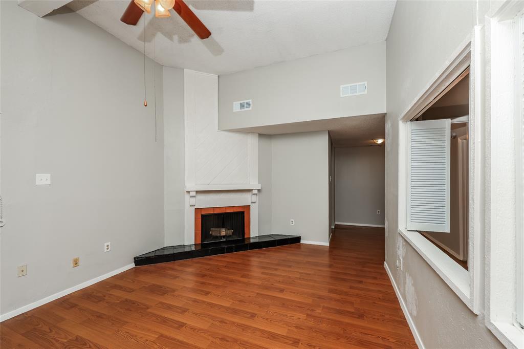 9696 Walnut Street, Unit 1216 Dallas, TX 75243 - Photo 4 of 16 Living area featuring wood-finish flooring and a corner fireplace with a black stone hearth
