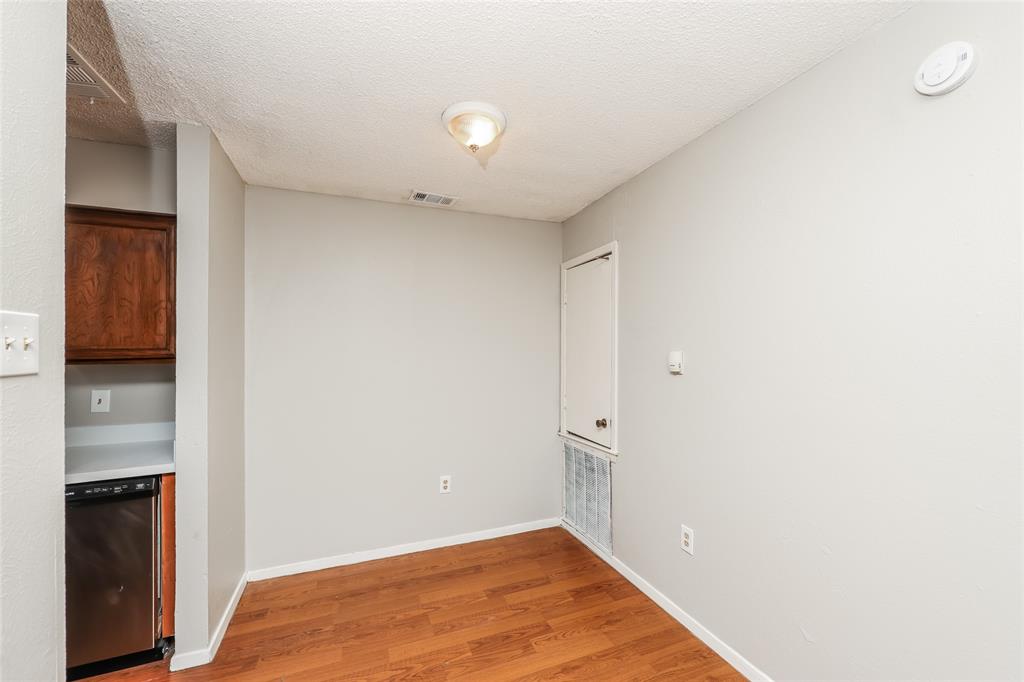 9696 Walnut Street, Unit 1216 Dallas, TX 75243 - Photo 9 of 16 Open-concept living space featuring wood-finish flooring, light gray wall paint, and a built-in kitchen nook with wood cabinetry