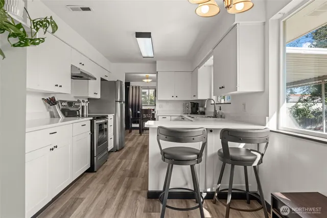 a kitchen with stainless steel appliances a stove a refrigerator and a white cabinets