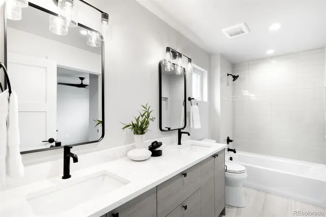 a bathroom with a double vanity sink toilet mirror and bathtub