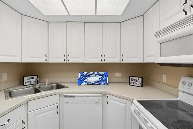 a kitchen with white cabinets and sink