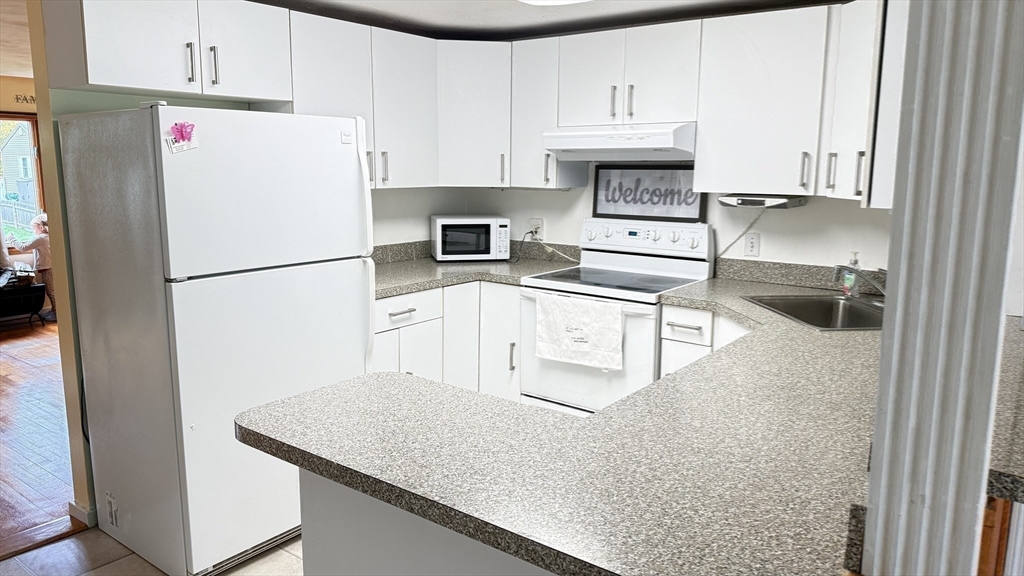 118 Spruce Road Norwood, MA 02062 - Photo 14 of 39 a kitchen with granite countertop a refrigerator sink stove and white cabinets