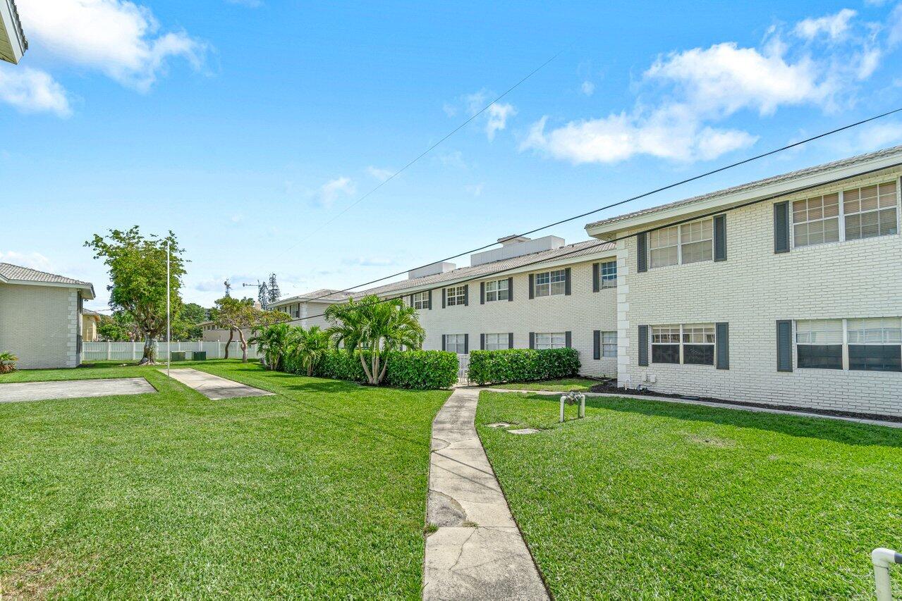 299 Southwest 7th Street, Unit 2060 Boca Raton, FL 33432 - Photo 19 of 20 a front view of a house with a yard and trees