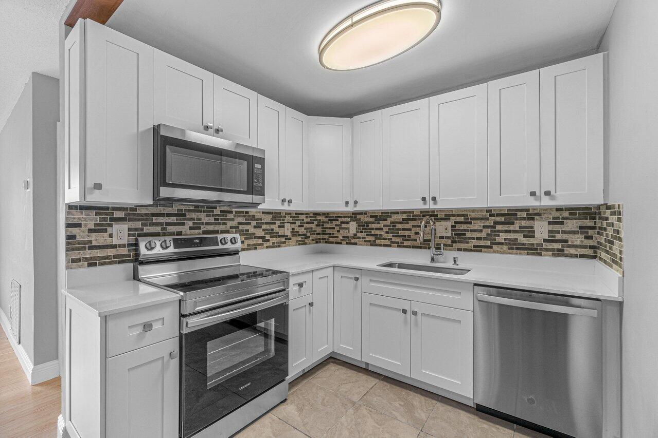 299 Southwest 7th Street, Unit 2060 Boca Raton, FL 33432 - Photo 5 of 20 a kitchen with white cabinets appliances and sink