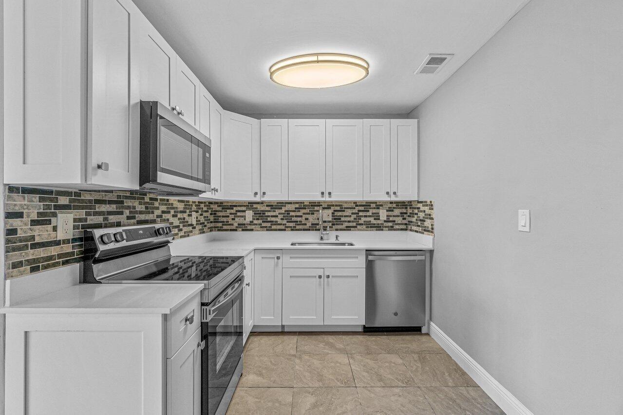 299 Southwest 7th Street, Unit 2060 Boca Raton, FL 33432 - Photo 7 of 20 a kitchen with stainless steel appliances granite countertop a stove a sink and a microwave