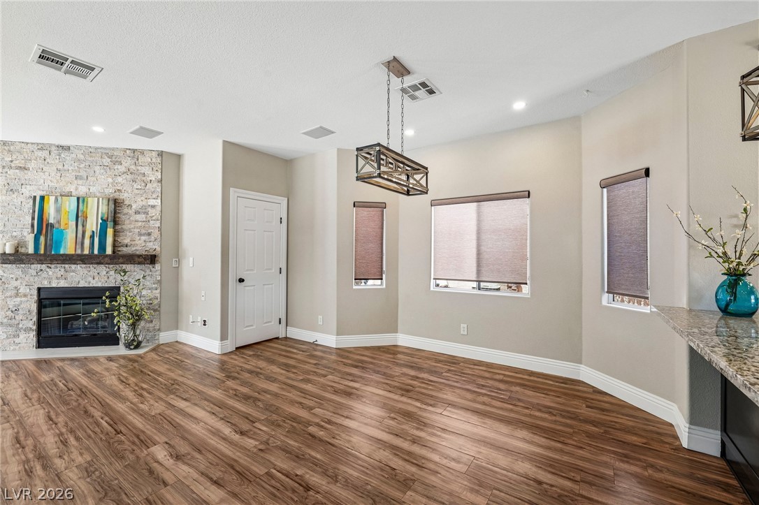 1176 Butternut Ranch Court Henderson, NV 89052 - Photo 10 of 60 A refined interior showcases a stone fireplace, sleek wooden flooring, and ample natural light from multiple windows.