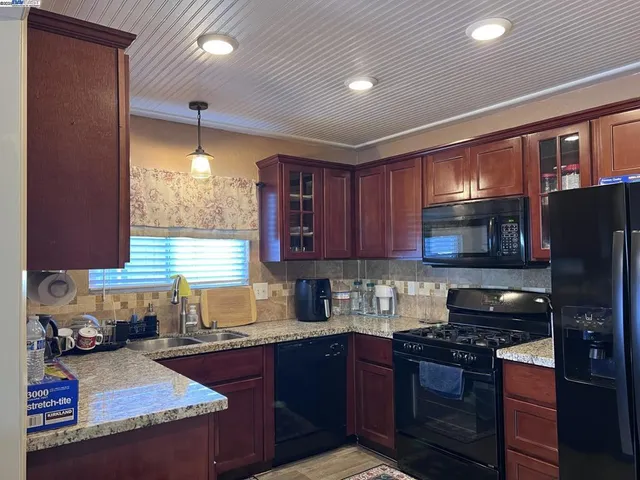 a kitchen with granite countertop wooden cabinets a stove top oven and stainless steel appliances