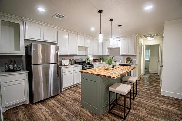 a kitchen with stainless steel appliances granite countertop a refrigerator a stove a sink dishwasher and a refrigerator with wooden floor