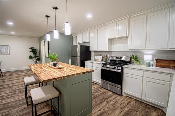 a kitchen with a stove a sink dishwasher a refrigerator with white cabinets and wooden floor