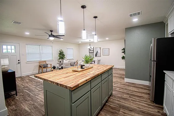 a room with kitchen island granite countertop a sink a counter space appliances and cabinets