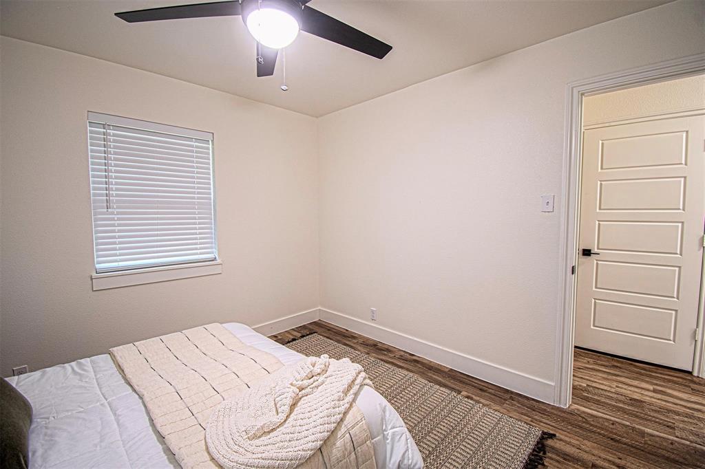 551 East Burks Street Pilot Point, TX 76258 - Photo 21 of 29 a bed in a bedroom next to a window and a chandelier