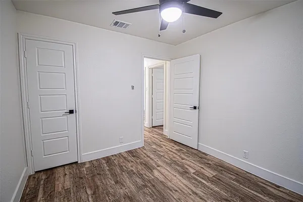 an empty room with wooden floor closet and chandelier fan