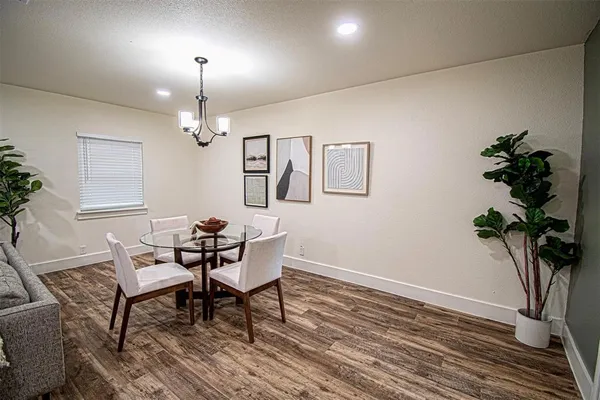 a dining room with wooden floor a chandelier a glass table and chairs