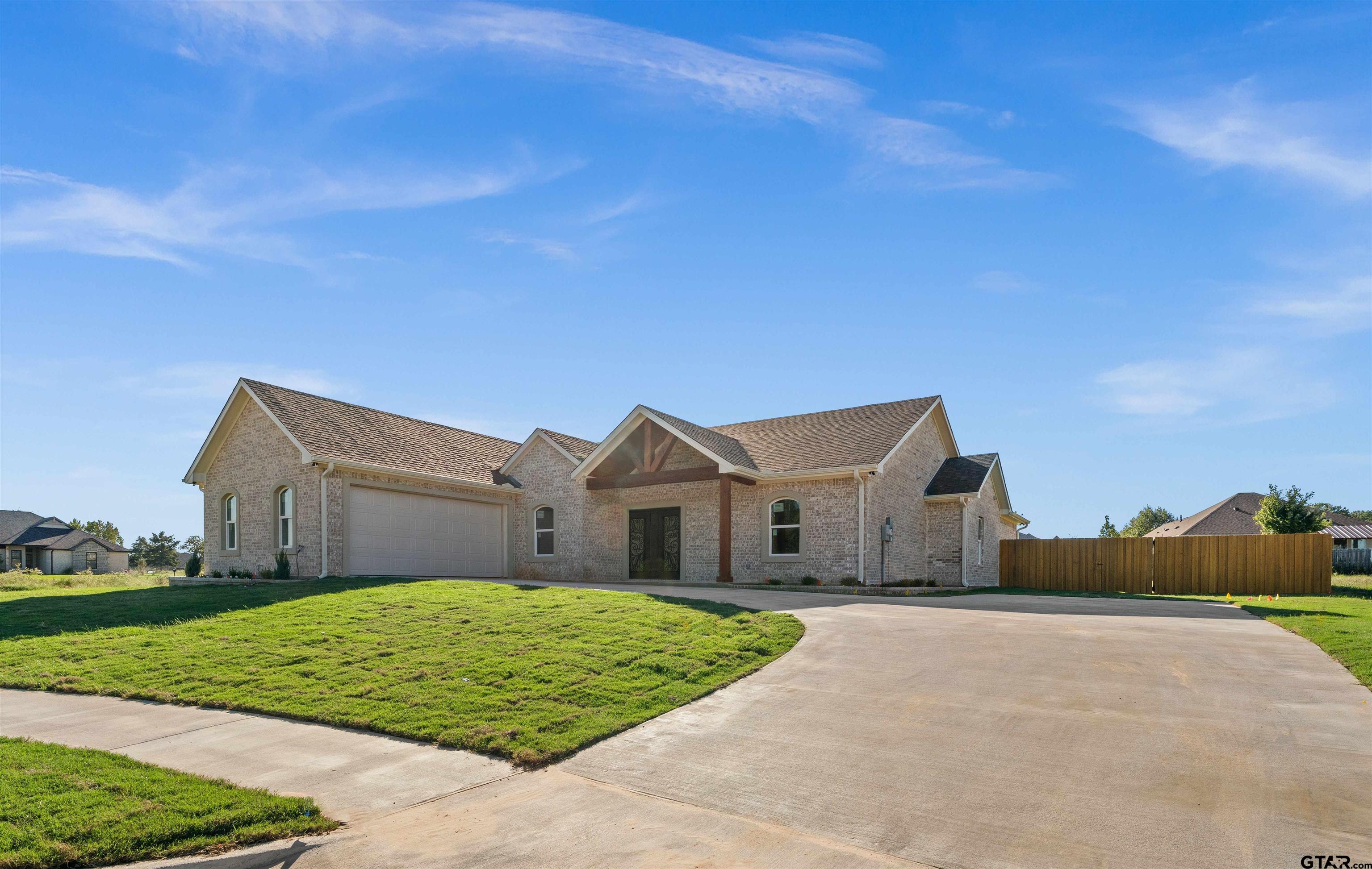 a view of house with a big yard and large tree