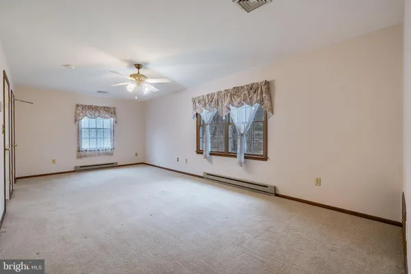 an empty room with windows and ceiling fan view