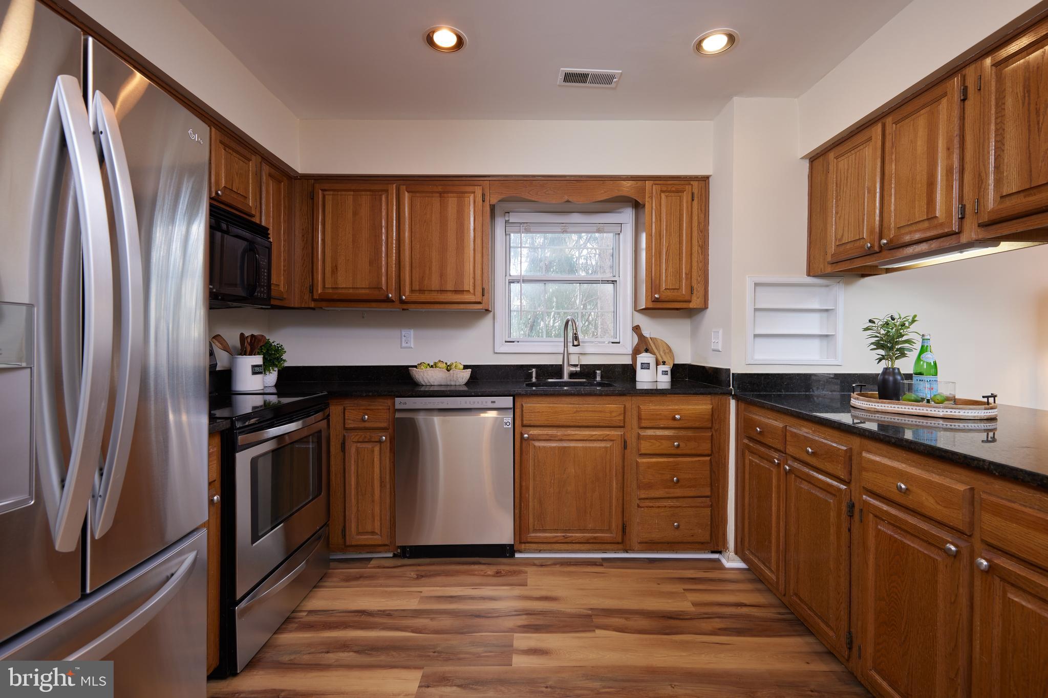 20100 Loading Rock Place Gaithersburg, MD 20886 - Photo 20 of 44 a kitchen with granite countertop stainless steel appliances and wooden cabinets
