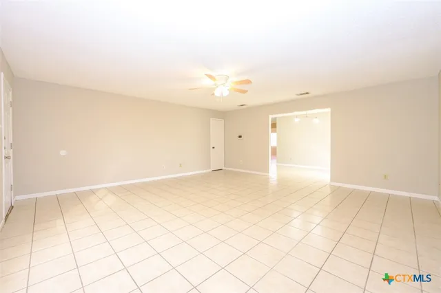 a view of an empty room and chandelier fan