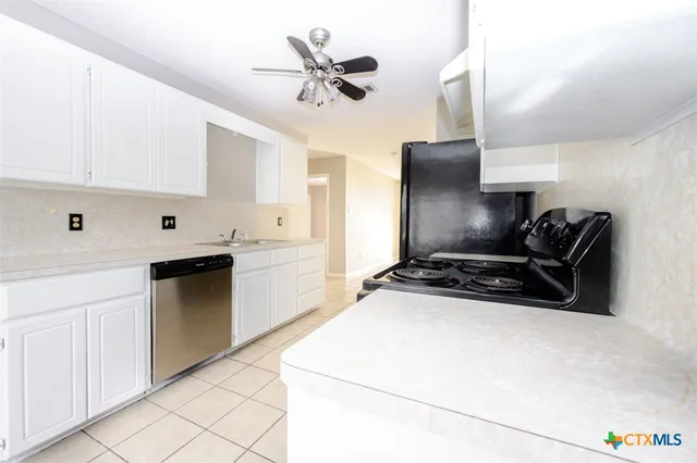 a kitchen with stainless steel appliances a stove a sink and white cabinets