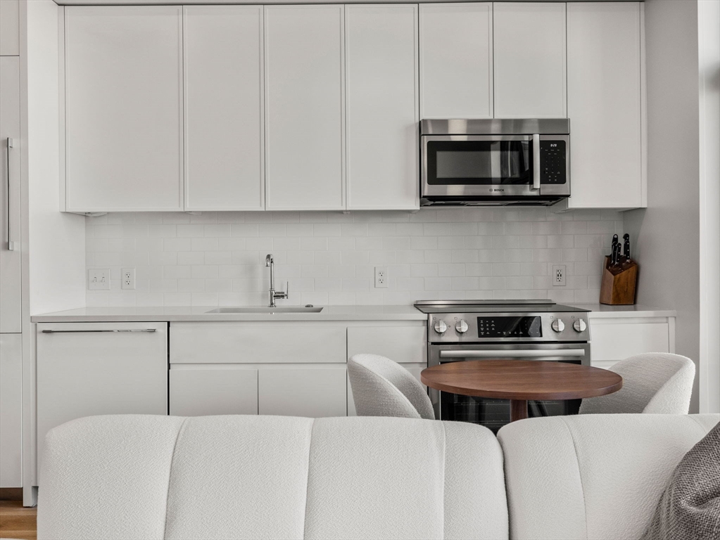 191 Washington Street, Unit 507 Boston, MA 02135 - Photo 3 of 23 a kitchen with stainless steel appliances a stove a microwave and sink