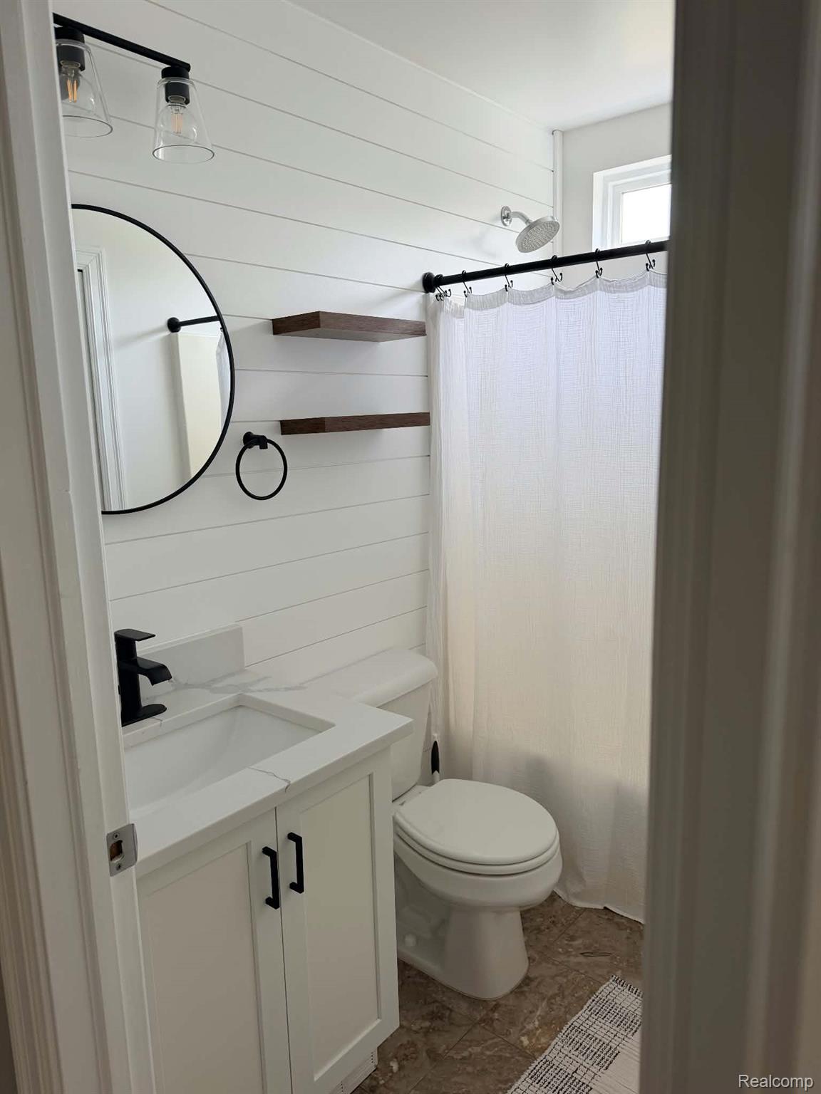 10070 Fenton Road Fenton, MI 48430 - Photo 12 of 21 White shiplap accent wall, vanity with white countertop, sleek black faucet, built-in shelving, and tiled flooring