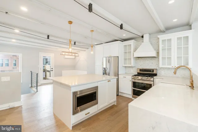 a kitchen with stainless steel appliances wooden floor and a refrigerator