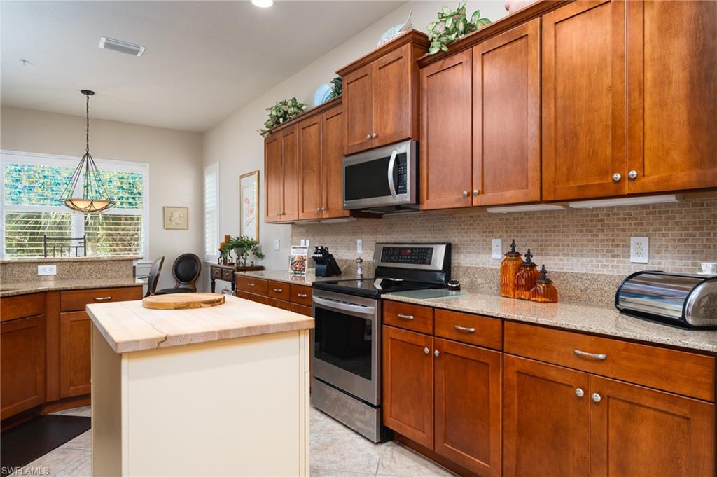 26479 Lucky Stone Road, Unit 202 Bonita Springs, FL 34135 - Photo 15 of 38 a kitchen with stainless steel appliances granite countertop a sink a stove a microwave and cabinets