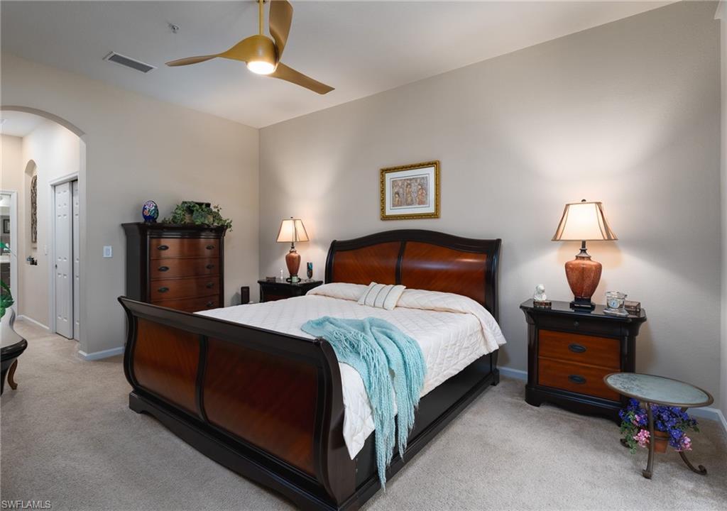 26479 Lucky Stone Road, Unit 202 Bonita Springs, FL 34135 - Photo 22 of 38 a spacious bedroom with a bed and a lamp on a dresser
