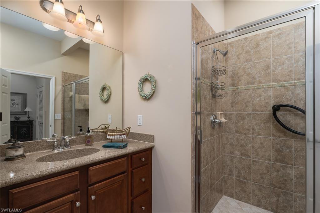 26479 Lucky Stone Road, Unit 202 Bonita Springs, FL 34135 - Photo 28 of 38 a bathroom with a granite countertop sink a mirror and shower