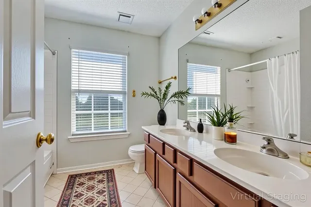 a bathroom with a double vanity sink a potted plant and a window