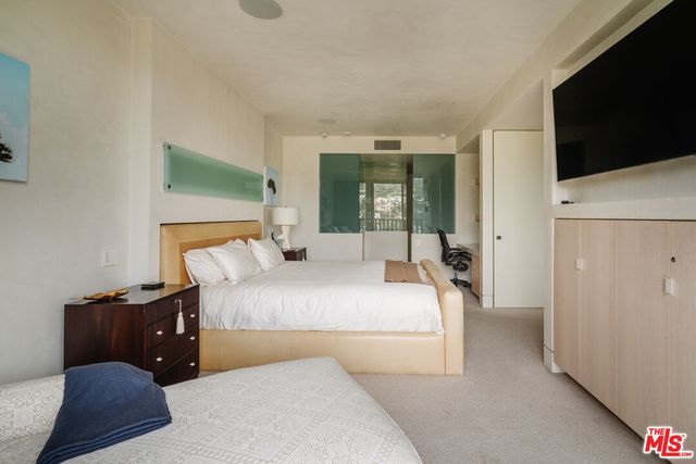 a bedroom with bed and flat tv screen on dresser