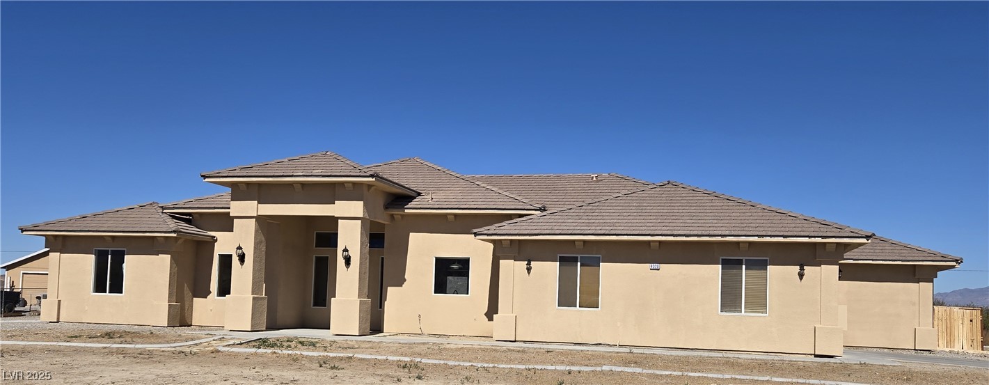 View of front facade featuring stucco siding and a tile roof