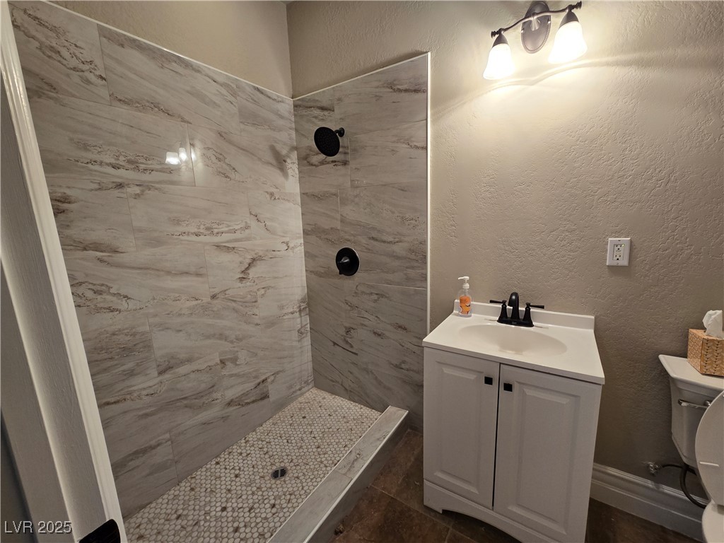 4320 Tiger Road Pahrump, NV 89048 - Photo 27 of 33 Full Guest bath featuring a textured wall, a shower stall, vanity, and dark tile patterned floors