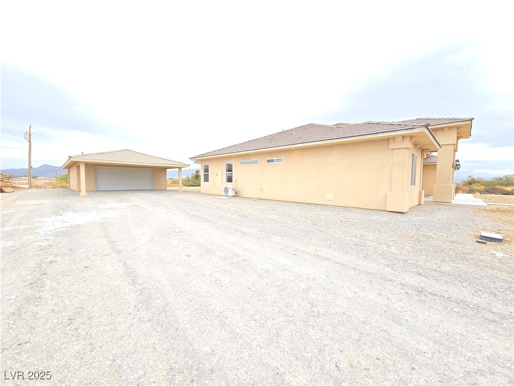 4320 Tiger Road Pahrump, NV 89048 - Photo 29 of 33 View of the left side of property featuring an outdoor structure, stucco siding, a detached garage, and a tile roof