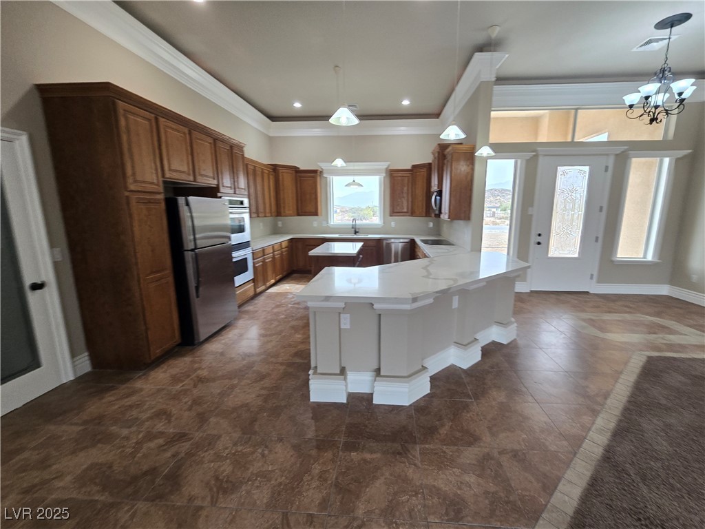 4320 Tiger Road Pahrump, NV 89048 - Photo 3 of 33 Kitchen featuring crown molding, brown cabinets, stainless steel appliances, a chandelier, and recessed lighting