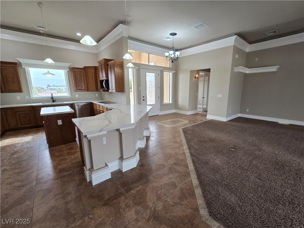 4320 Tiger Road Pahrump, NV 89048 - Photo 4 of 33 Kitchen with crown molding, pendant lighting, a chandelier, a center island, and brown cabinetry