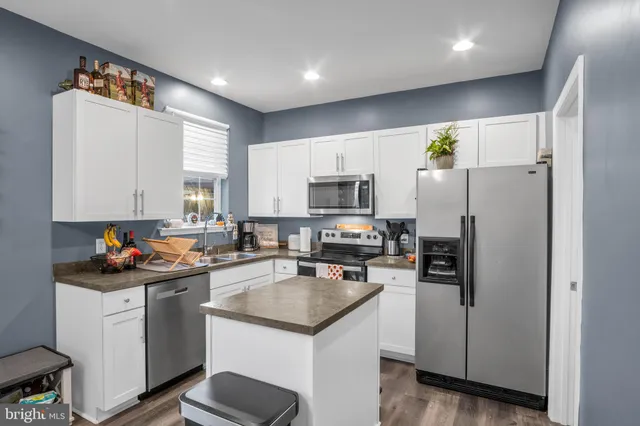 a kitchen with stainless steel appliances granite countertop sink stove and white cabinets with wooden floor