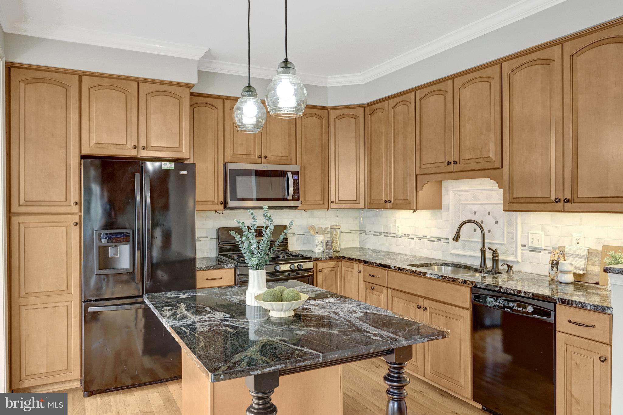 43233 Stillforest Terrace Ashburn, VA 20147 - Photo 7 of 24 a kitchen with kitchen island granite countertop a sink stove and refrigerator