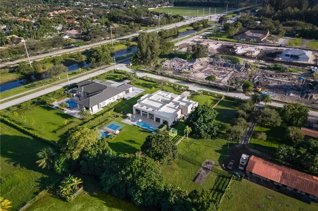 an aerial view of residential houses with outdoor space and trees