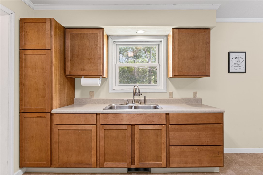 322 Tribble Street Honea Path, SC 29654 - Photo 15 of 35 Rich wood cabinetry surrounds a central sink below a bright window overlooking nature.