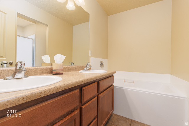 6761 950 East Midvale, UT 84047 - Photo 22 of 44 Bathroom featuring a dual-sink vanity with a speckled countertop, undermount sinks, and a built-in tub