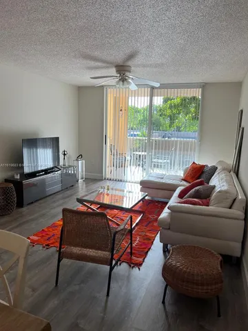 a living room with furniture a flat screen tv and a large window