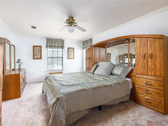 a spacious bedroom with a bed a dresser and a chandelier