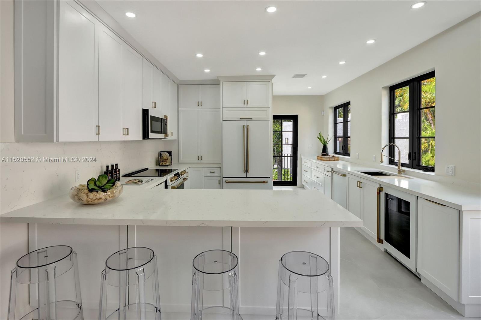 Granada Coral Gables, FL 33134 - Photo 16 of 36 a kitchen with stainless steel appliances a sink a stove a refrigerator island white cabinets and a granite counter tops